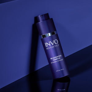 Blue anti-aging skincare bottle leans on a blue wall in a clinical setting